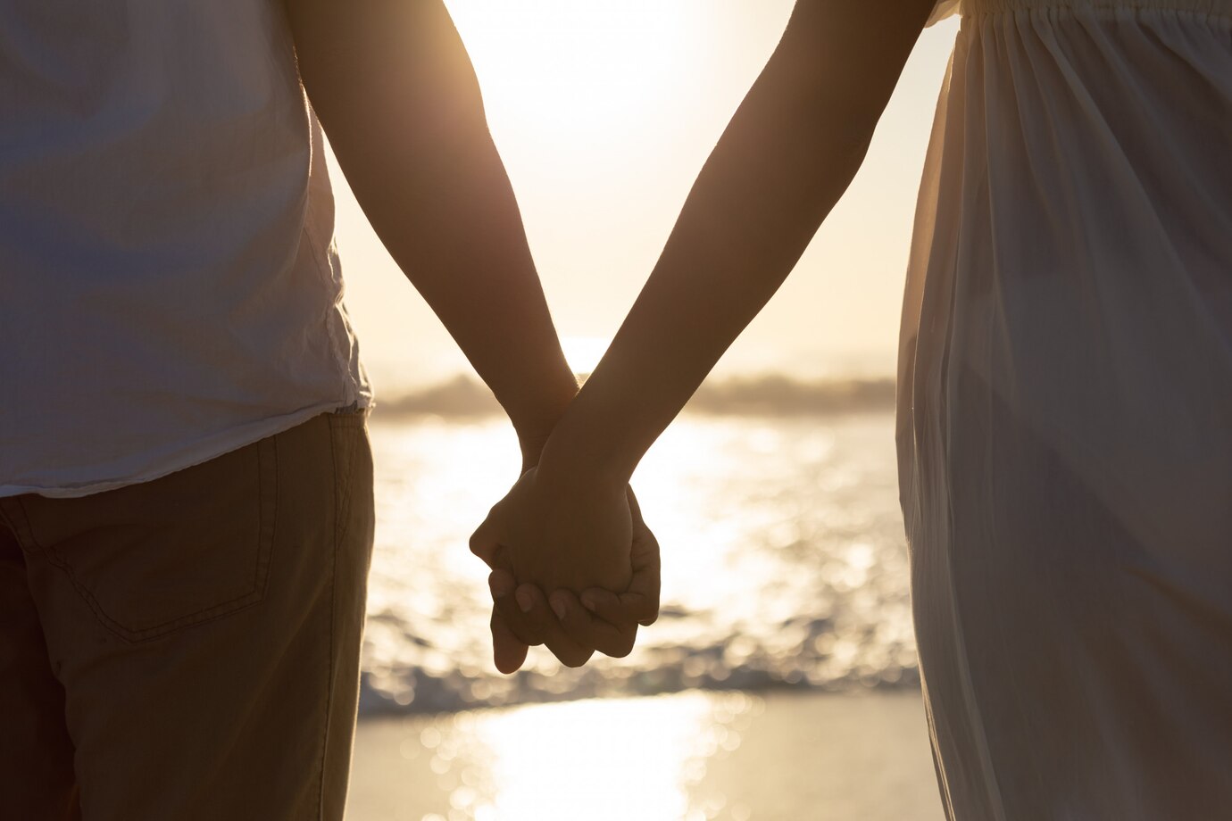 couple-standing-together-hand-hand-beach_107420-10016